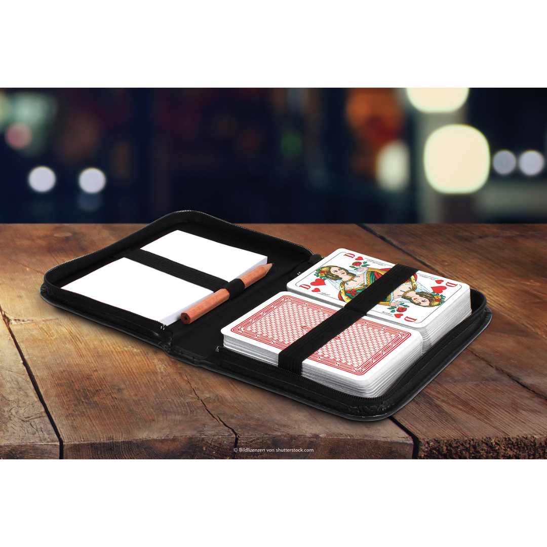 Schwarzes Spielkarten-Etui aus Kunstleder mit ASS Spielkarten Rommé geöffnet mit dem sichtbaren Inhalt zweier Kartendecks, einem Block und einem Bleistift auf einem Holztisch.