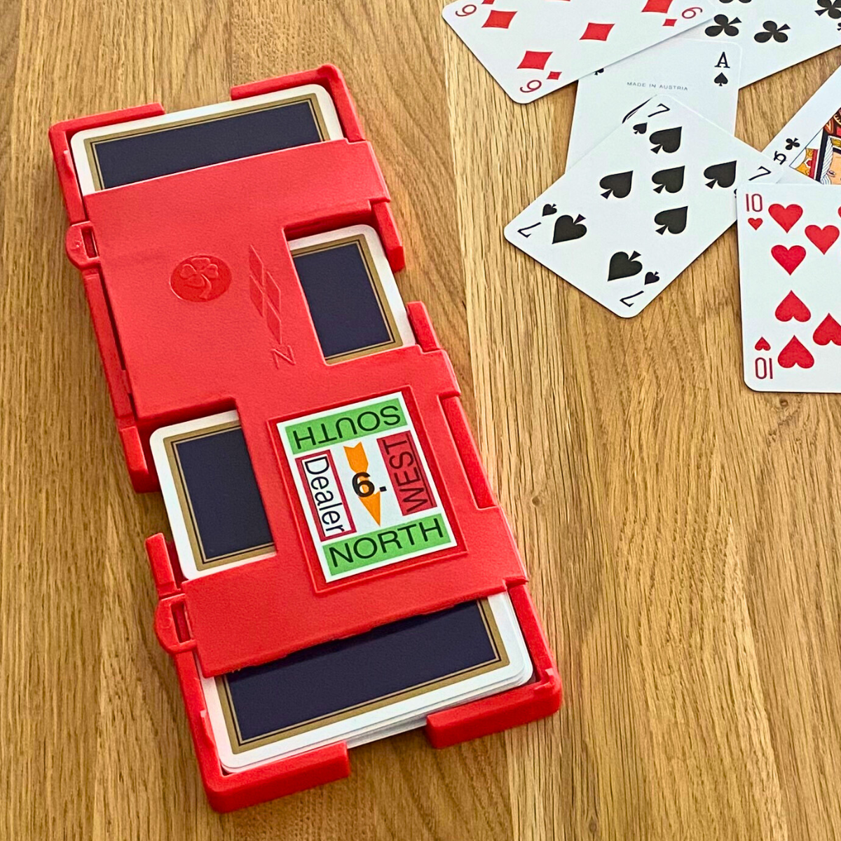 Bridge Board (Hardboard Super Plus) mit eingesteckten Spielkarten auf Holztisch