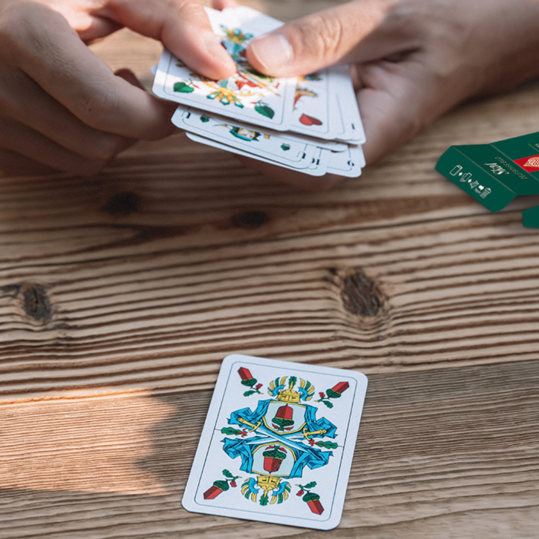 Es wird Skat gespielt, mit Skatkarten, deutsches Bild - Austeilung der Karten am Holztisch