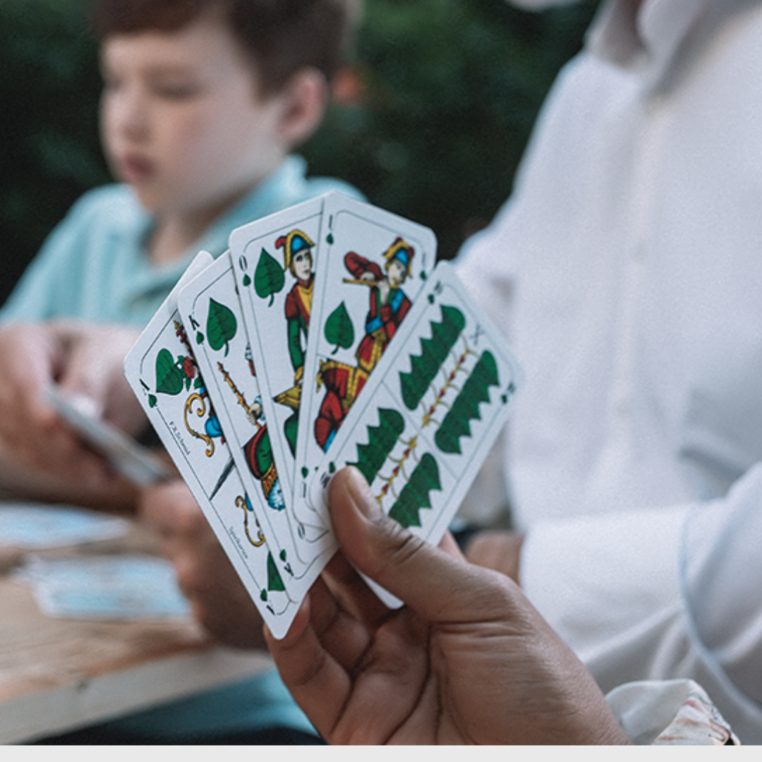 Spielrunde am Tisch mit Männern und einem Jungen - gespielt wird Schafkopf Tarock mit bayerischen Bild