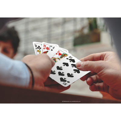 Eine Hand hält einen Kartenfächer mit den ASS Doppelkopf-Spielkarten in Premium Leinen-Qualität.