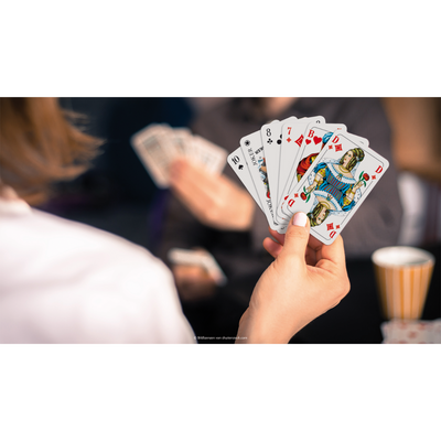 Eine Hand hält einen Kartenfächer mit den ASS Rommé Spielkarten.