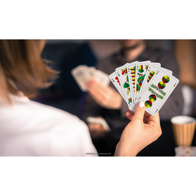 Eine Hand hält einen Kartenfächer mit den ASS Tarock/Schafkopf Spielkarten.