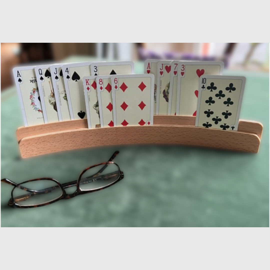 Zweireihiger Kartenhalter aus Holz stehend auf Bridgetisch mit 13 Spielkarten sortiert nach Farben auf zwei Ebenen.