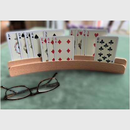 Zweireihiger Kartenhalter aus Holz stehend auf Bridgetisch mit 13 Spielkarten sortiert nach Farben auf zwei Ebenen.