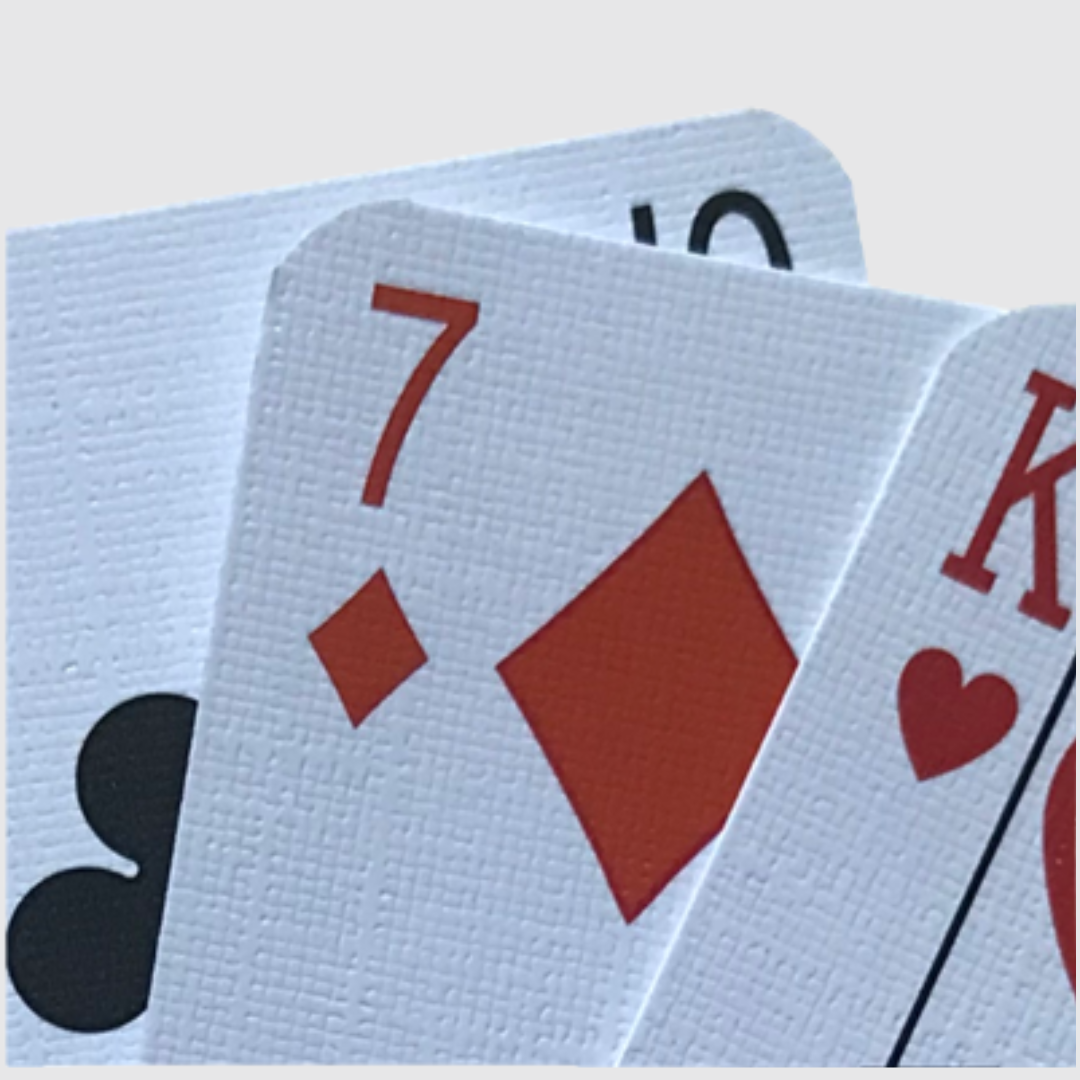 Nahaufnahme eines Kartenfaechers von Spielkarten mit Leinenstruktur, auf der die rauere Oberflaeche sichtbar ist. 